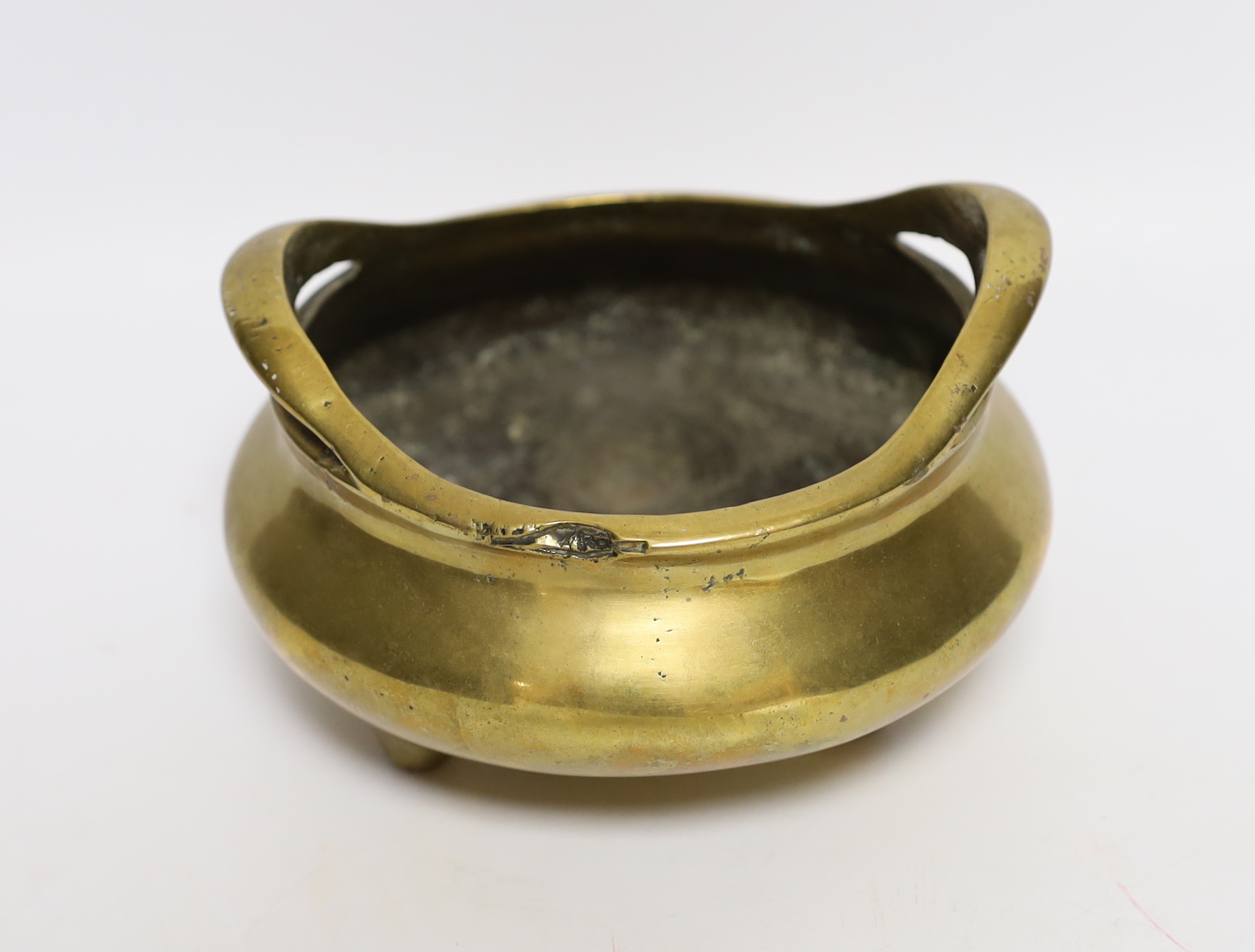 A Chinese bronze tripod censer with twin handles, mark to the base, 14cm wide